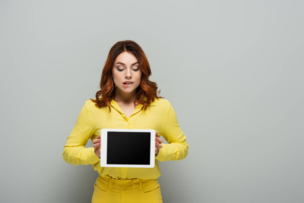 mulher curiosa segurando tablet digital com tela em branco no cinza - Foto, Imagem