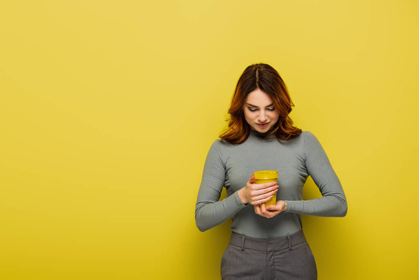 młoda kobieta z kręconymi włosami trzymając papierowy kubek na żółto - Zdjęcie, obraz