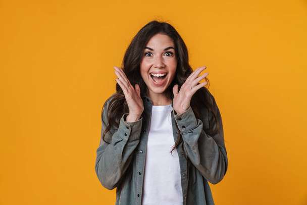 Excited beautiful girl expressing surprise at camera isolated over yellow background - Foto, imagen