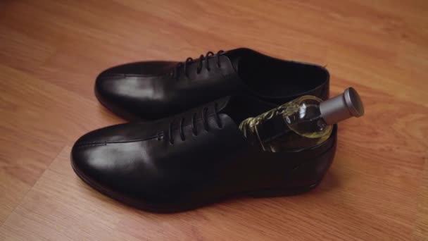Un colpo ravvicinato di scarpe da uomo e profumi sul pavimento. Eleganti scarpe in pelle nera. Profumi di lusso. - Filmati, video