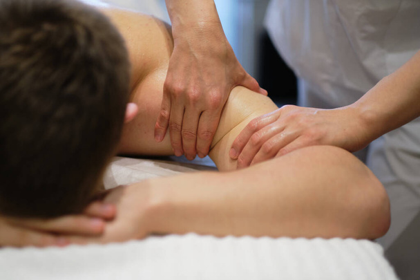 Gros plan de l'homme profitant d'un massage relaxant des épaules. Homme relaxant sur table de massage recevant massage - Photo, image