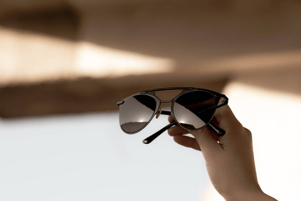 Modelo de gafas de sol de ojo de gato de moda para mujeres tienen en la mano disparar al aire libre en un primer plano día de verano. Enfoque selectivo  - Foto, Imagen