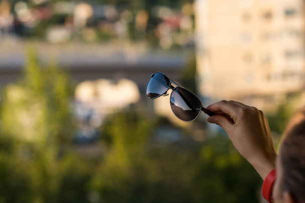 Módní kočka oko sluneční brýle model pro ženy držet v ruce střílet venku v letní den detailní záběr. Selektivní zaměření  - Fotografie, Obrázek