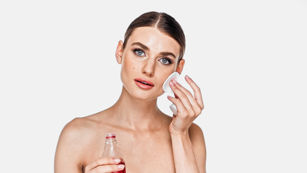 Young adult woman applying toner on face with cotton pad isolated on white - Photo, Image