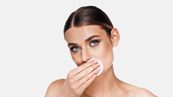 Young woman removing makeup on lips with cotton pad isolated on white - Photo, Image