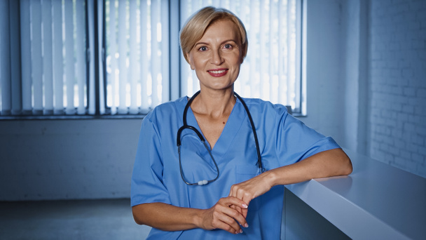 Smiling mature doctor in uniform looking at camera in clinic  - Photo, Image