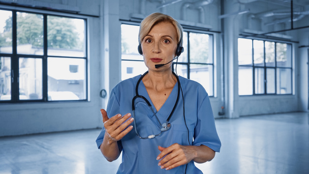 Doctor en auriculares hablando en cámara en el hospital  - Foto, Imagen