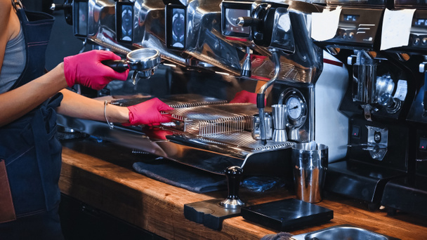 bijgesneden weergave van barista holding portafilter in de buurt van professionele koffiezetapparaat  - Foto, afbeelding