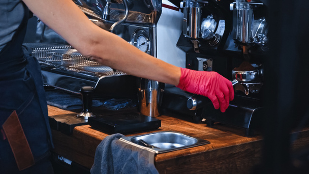 cropped view of barista in latex glove holding portafilter with ground coffee in coffee shop - Photo, Image