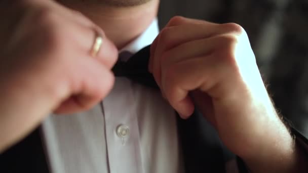Dichtbij een man met een strikje. Bruidegom maakt zich klaar voor de bruiloft. jong volwassene zetten op zijn zwart strik. - Video