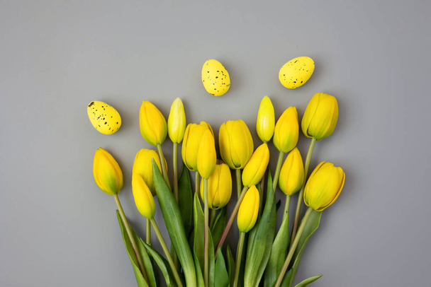 Tulipes jaunes et oeufs de Pâques sur fond gris. Couleur tendance de l'année 2021. Illuminating Yellow and Ultimate Gray. Espace de copie. Le printemps. Concept de fleur minimale créative. - Photo, image