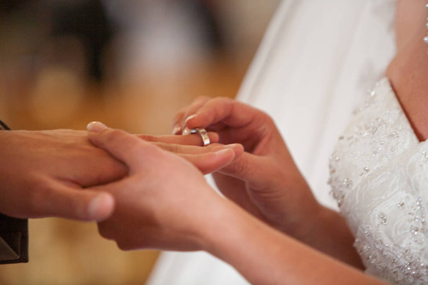Közelkép a menyasszonyról, amint jegygyűrűt húz a vőlegény ujjára. Jegygyűrűt cserélnek.. - Fotó, kép