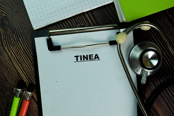 Tinea écrit sur une paperasse isolée sur Wooden Table. Concept médical ou de santé - Photo, image