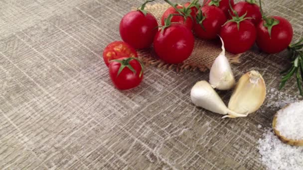 Fechar-se de ramo de tomates molhados, garlics e colher com sal na mesa de cozinha de madeira
 - Filmagem, Vídeo