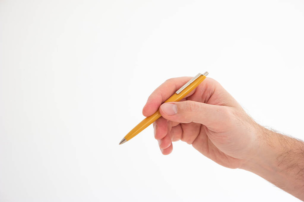 Bolígrafo plástico vintage amarillo sostenido en la mano por mano masculina caucásica haciendo gesto estudio tiro aislado en blanco. - Foto, Imagen
