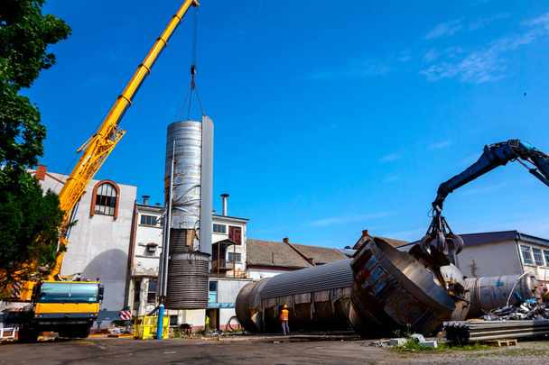 Máquina de carga com garra de garra hidráulica e guindaste estão derrubando silo de metal pesado no complexo industrial
. - Foto, Imagem