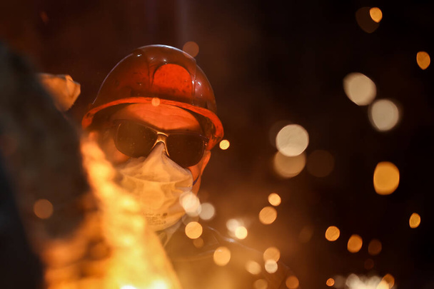 Ein Stahlbauer gießt Roheisen aus einem Hochofen, Funken und Spritzer heißes Metall fliegen. - Foto, Bild