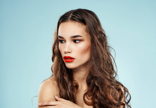 Γυναίκα κόκκινα χείλη μπλε φόντο γυμνοί ώμοι σγουρά μαλλιά hairstyle μοντέλο - Φωτογραφία, εικόνα