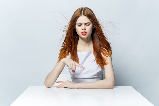 bella donna dai capelli rossi seduta a tavola gesto mani emozioni e modello labbra rosse - Foto, immagini