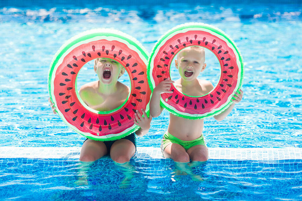 Μικρά χαριτωμένα παιδιά κοντά στην πισίνα. Τα παιδιά διασκεδάζουν το καλοκαίρι. - Φωτογραφία, εικόνα