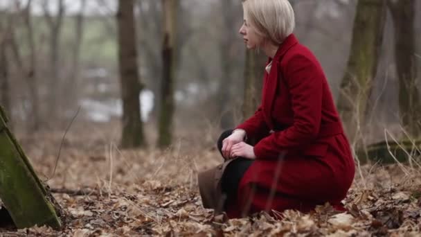 dziewczyna w czerwonym płaszczu na opuszczonym cmentarzu przy grobie - Materiał filmowy, wideo