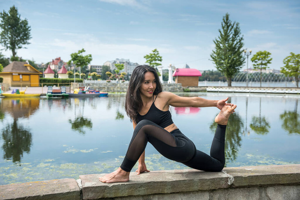 Nuori hoikka nainen joogaharjoituksissa lähellä järveä. Käsite rauhallinen ja meditaatio - Valokuva, kuva