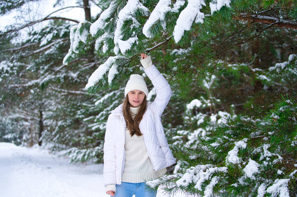 bella sorridente giovane donna in inverno all'aperto. Concetto invernale. vestiti bianchi, neve, foresta, freddo, congelato - Foto, immagini