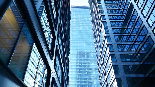 Вид снизу на современные небоскребы в деловом районе на фоне голубого неба. Взгляд на деловые здания в центре города. - Фото, изображение