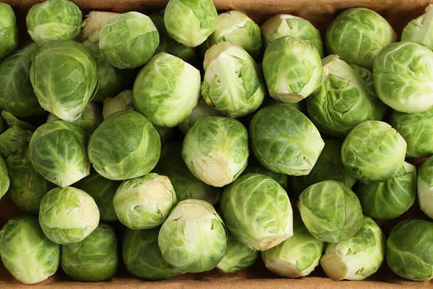 The heads of Brussels sprouts are randomly placed in a cardboard box. Closeup. View from above - Photo, Image