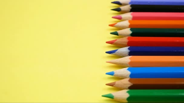 Цветные карандаши сырые с красным карандашом, выделяющимся из толпы на желтом фоне - Кадры, видео