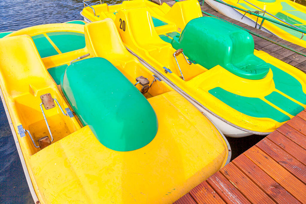 Pedal tekneleri ya da sandallar katamaran istasyonu. Sarı su bisikletleri güneşli yaz gününde marina rıhtımında kilitli. Açık havada yaz tatili aktivitesi - Fotoğraf, Görsel