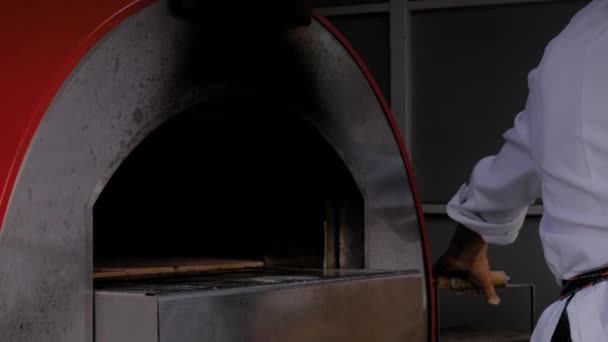 Séf bácsi, a pék pizzát tesz egy modern fémsütőbe az étteremben. - Felvétel, videó