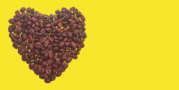 Сердце кофейных зерен на желтом фоне. Копирование пространства. - Фото, изображение