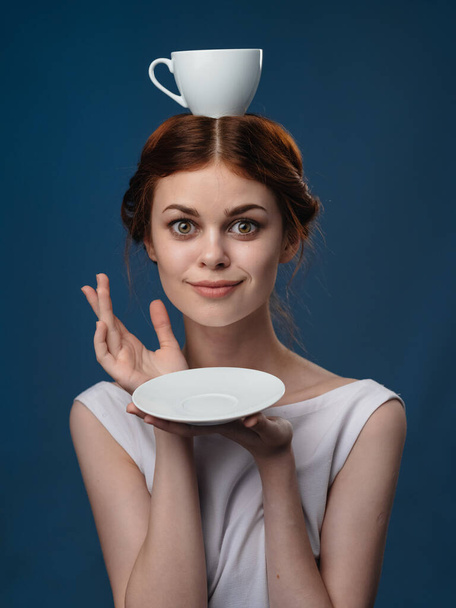 Gyönyörű nő világos ruhák kávéscsésze és csészealj kék háttér modell portré - Fotó, kép