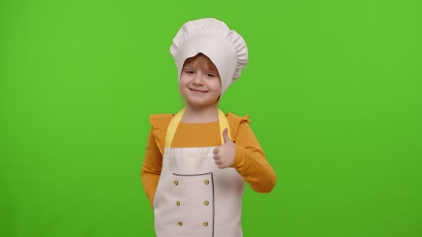 Kind meisje kind gekleed als kok chef-kok tonen duimen omhoog, glimlachen, kijken naar camera op chroma sleutel - Video