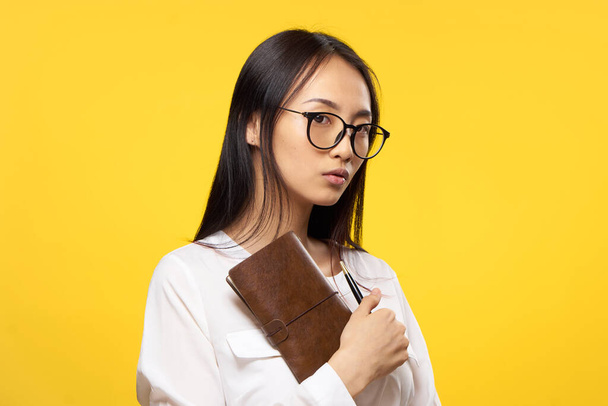 Business woman with glasses notepad in the hands of manager office yellow background - Photo, image