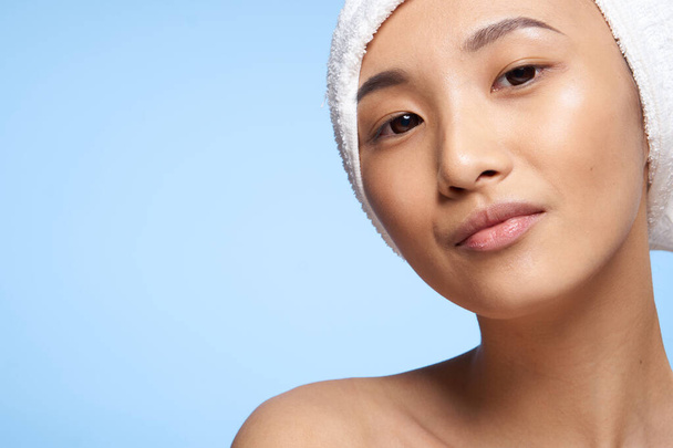 woman with bare shoulders towel on head close-up blue spa treatment background - Photo, Image