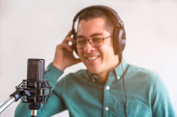 Porträt eines jungen Mannes, der einen Podcast live von zu Hause aus betreibt. Er hat Kopfhörer - Foto, Bild