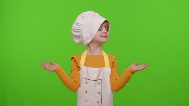 Dziecko dziewczynka dziecko ubrane kucharz w fartuch wskazując na prawo i lewo na puste miejsce, klawisz chroma - Materiał filmowy, wideo