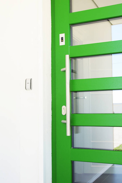 Bejárati ajtó, bejárati ajtó elektromágneses zárral. Egy zöld ajtó mágneses zárral, mint biztonsági ajtó beléptető rendszer.  - Fotó, kép