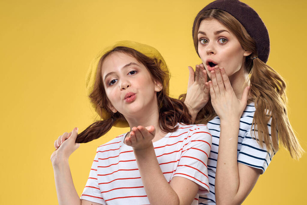Hermanas alegres en sombreros rayas camisetas alegría estilo de vida amarillo fondo familia - Foto, imagen