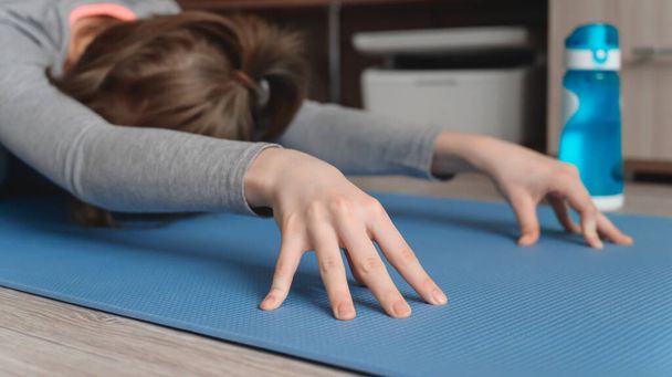 Teenage girl doing fitness exercise, practicing yoga at home. Healthy lifestyle concept. Workout at home. Home interior, natural light. Selective focus - Photo, Image