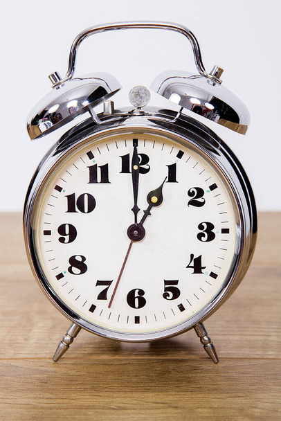 Metallic retro alarm clock on wooden isolated background. - Photo, Image