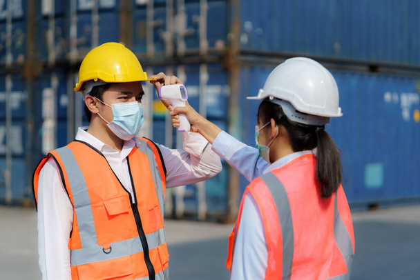 Asijské žena předák skenování horečka teplota s digitálním teploměrem na její zaměstnance pracovník nosí hygienické obličejové masky ochranu před coronavirem nebo COVID-19. - Fotografie, Obrázek