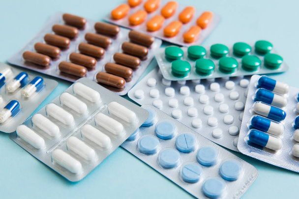 Différents comprimés, pilules, comprimés plaquettes thermoformées, sur fond bleu. Concept de soins de santé. Concentration sélective. - Photo, image