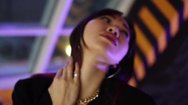Porträt eines asiatisch aussehenden Mädchens, das in die Kamera blickt, in Neonfarbe - Filmmaterial, Video