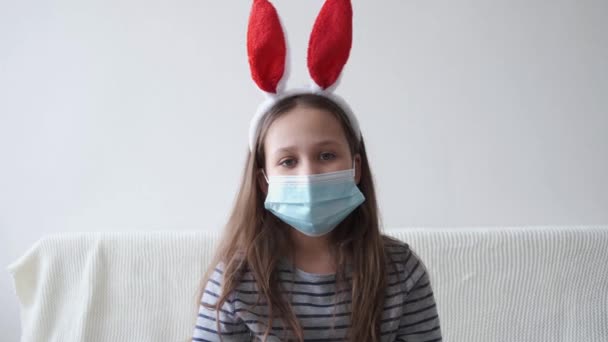 4k. piccola ragazza carina in maschera protettiva viso in orecchie di coniglio. pasqua - Filmati, video