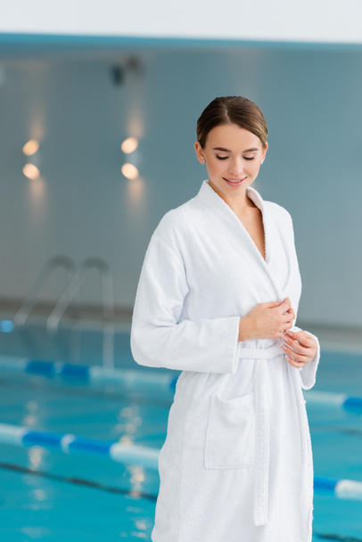 happy young woman in white bathrobe looking down in spa center  - Photo, Image