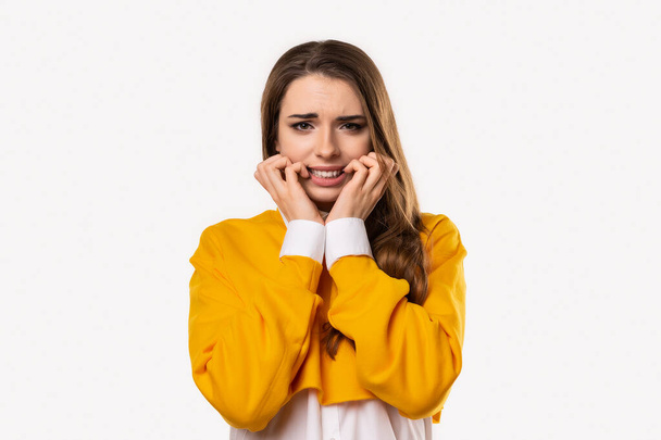 Portrait of scared brunette girl hold hands near mouth trembling fear, very terrified over scary creepy sound, standing in stupor over white background - Photo, Image