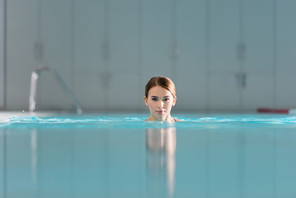 красивая молодая женщина плавает в бассейне роскошного спа-центра  - Фото, изображение